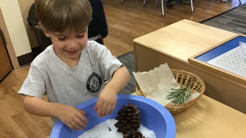 Child playing with snow in a bowl
